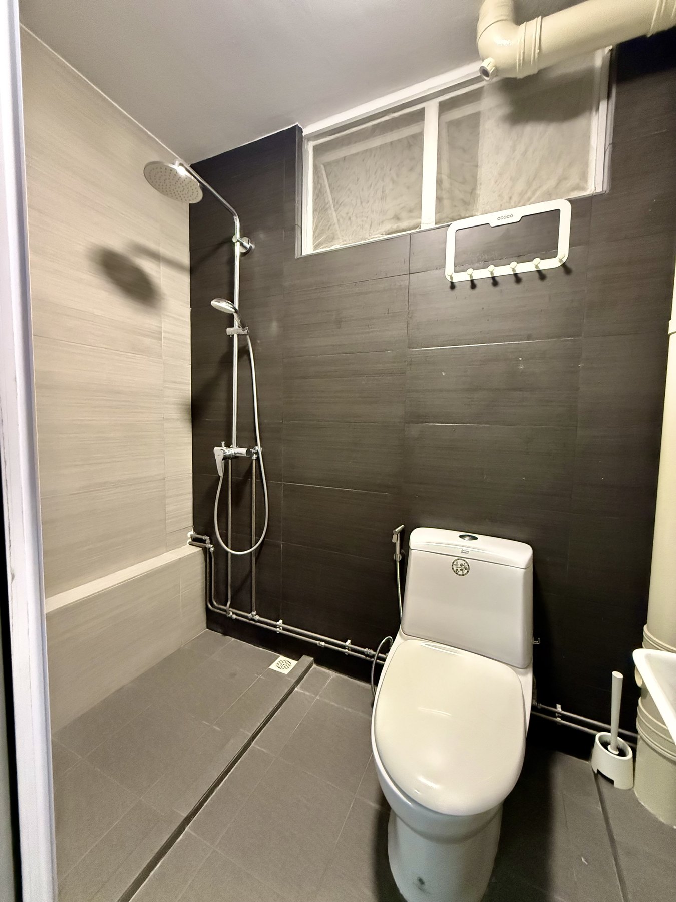 Updated HDB bathroom with shower area and dark feature wall tiles
