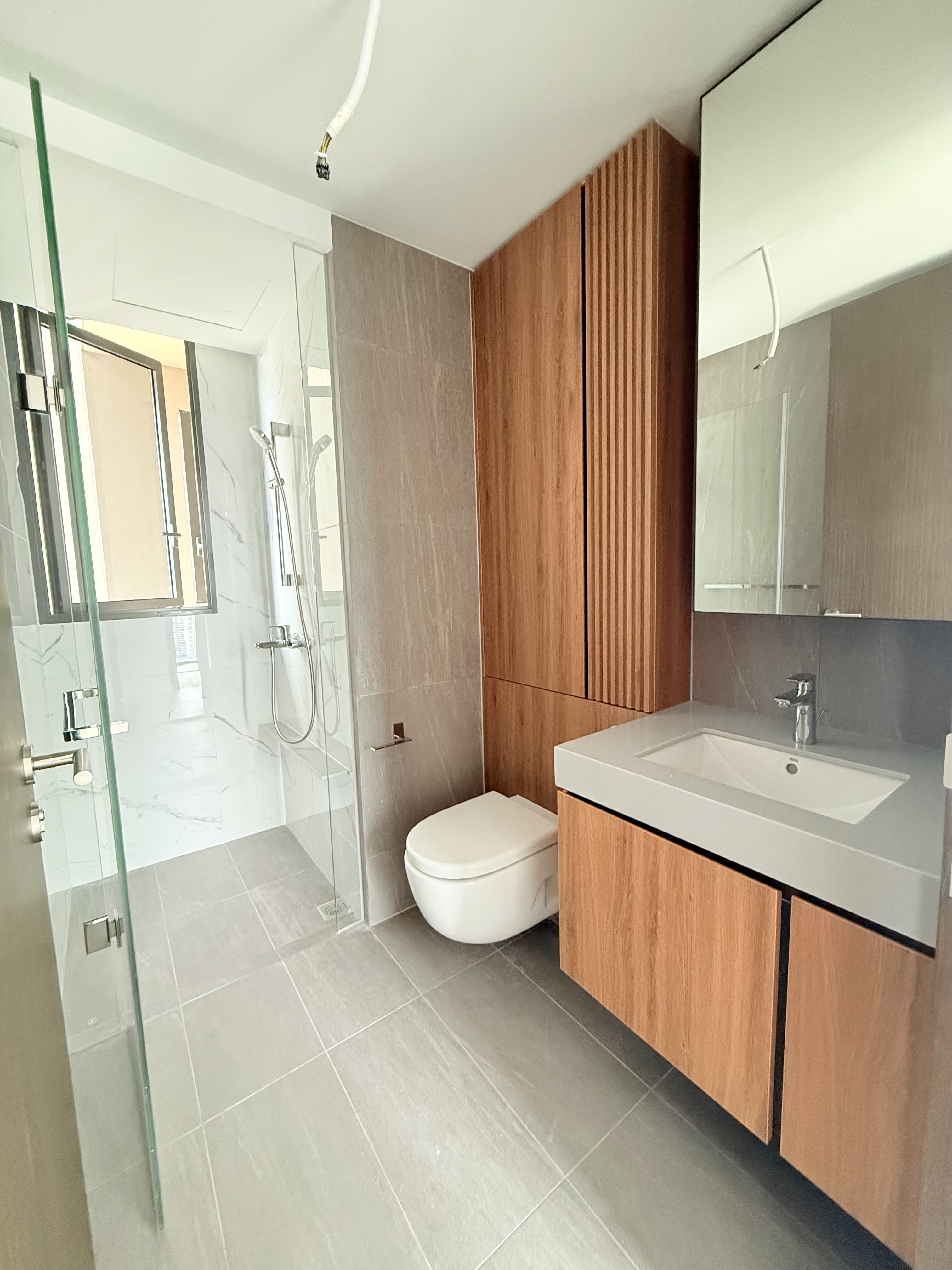 Common bathroom at AMO Residence with timber-look vanity and glass shower